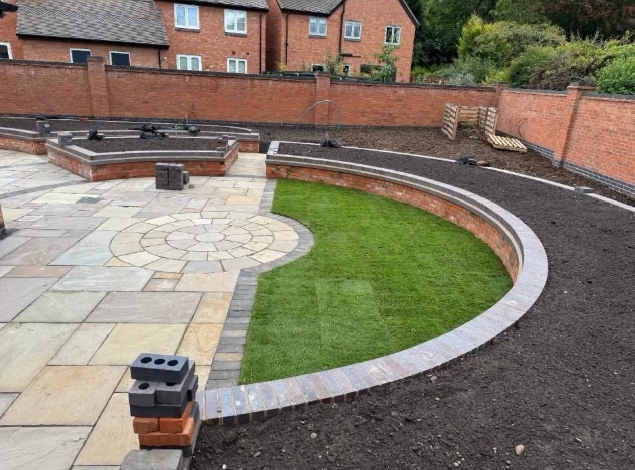 Curved brick retaining wall around new lawn